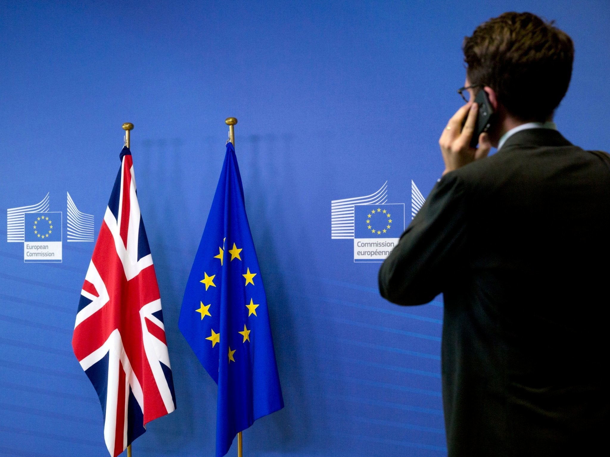 A member of the British delegation speaks on a mobile phone prior to the arrival of Britain's Secretary of State for Exiting the European Union Dominic Raab and EU chief Brexit negotiator Michel Barnier at EU headquarters in Brussels on Friday, Aug. 31, 2018