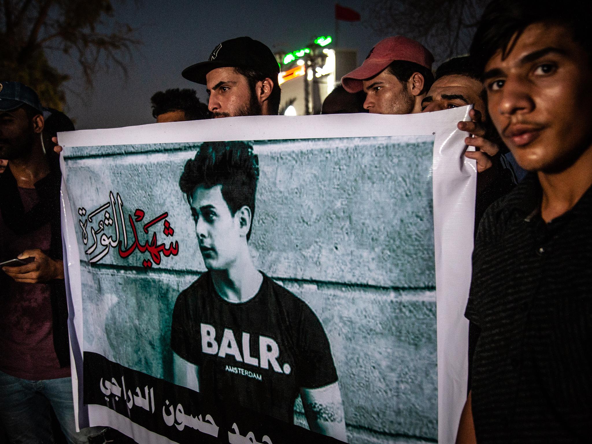 Young men hold posters of protesters killed in clashes with security forces during protests against water shortages in Basra