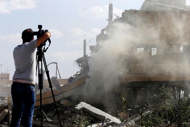 A journalist films the wreckage of the Scientific Studies and Research Centre in Barzeh, southern Syria, in 2018