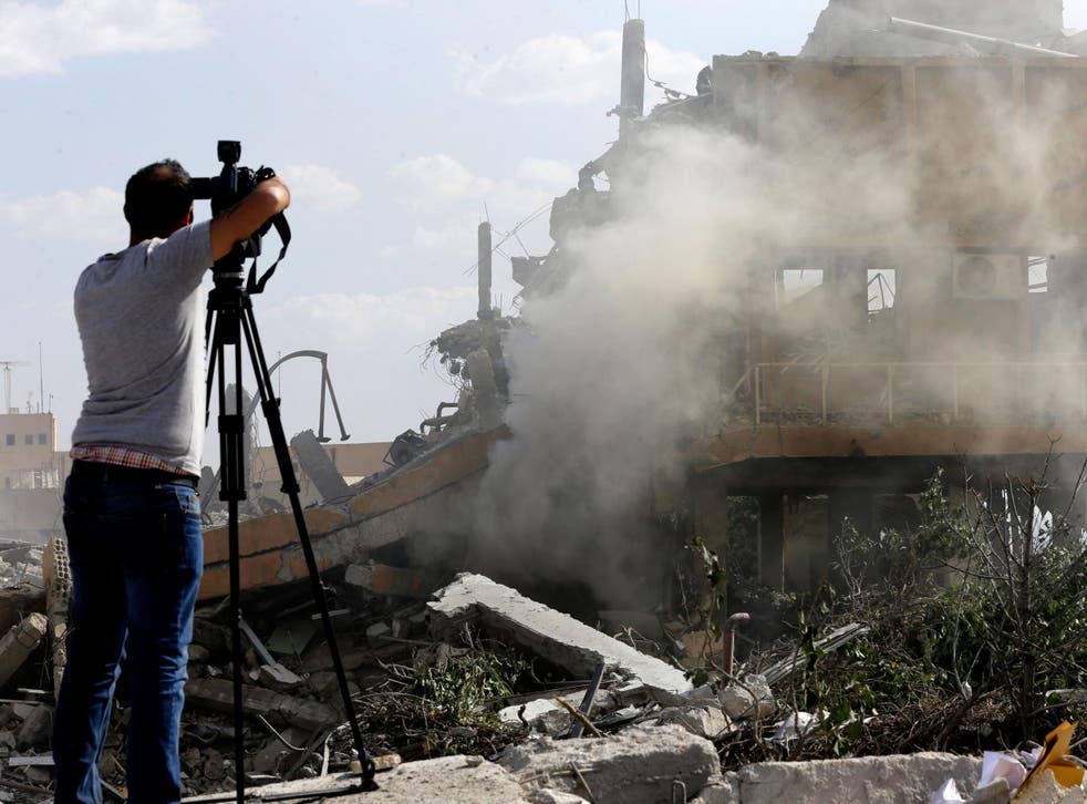 A journalist films the wreckage of the Scientific Studies and Research Centre in Barzeh, southern Syria, in 2018