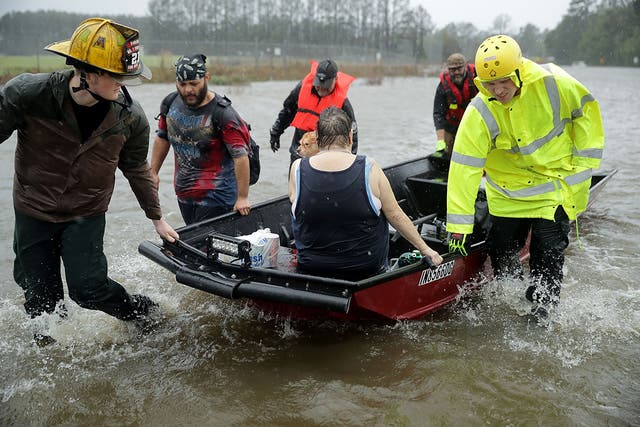 Fire department workers and volunteers rescue a woman and her dog from their flooded home in James City, North Carolina