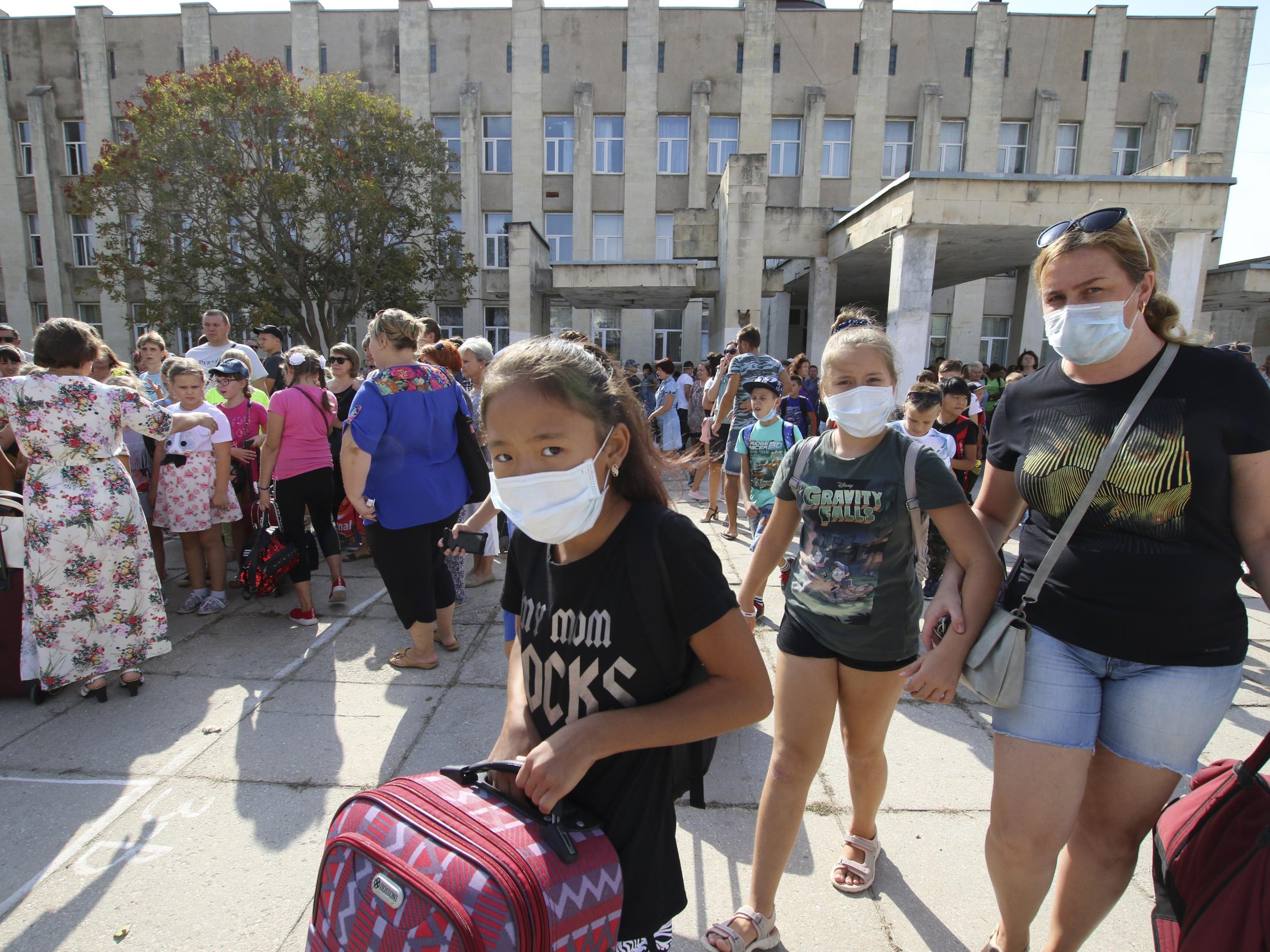 People wear protective masks during an evacuation of school-aged children due to concerns over air pollution in the town of Armyansk in Crimea, 4 September 2018