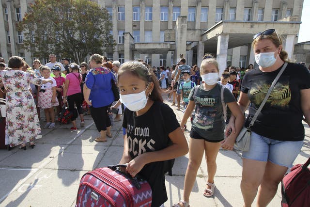 People wear protective masks during an evacuation of school-aged children due to concerns over air pollution in the town of Armyansk in Crimea, 4 September 2018