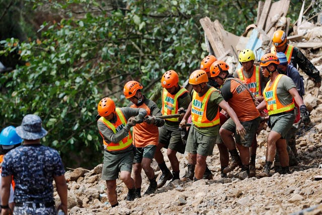 Rescue volunteers carry the body of a landslide victim in Ucab village, Philippines