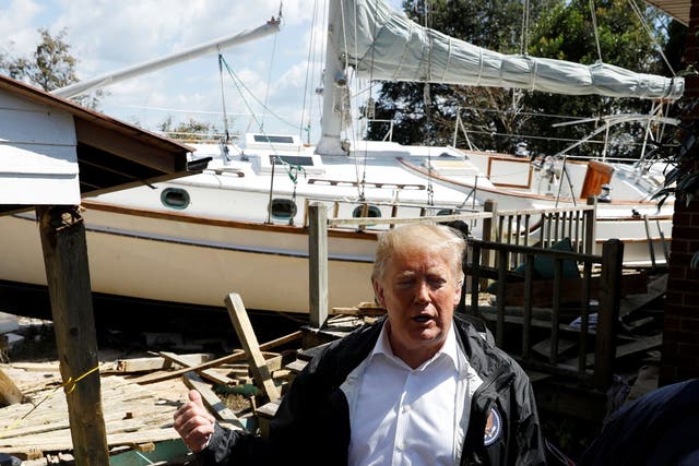 Donald Trump stands in front of a damaged sailboat while touring Hurricane Florence damage in New Bern, North Carolina