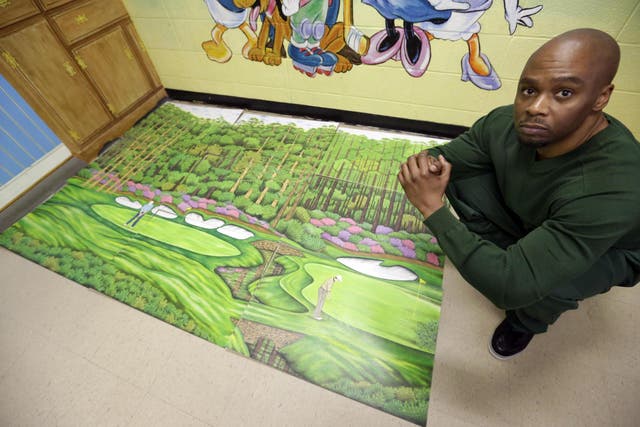 In the 16 May 2013 file photo, former Attica Correctional Facility inmate Valentino Dixon poses with his golf art he created in prison which ultimately led to a review of his case and his release.