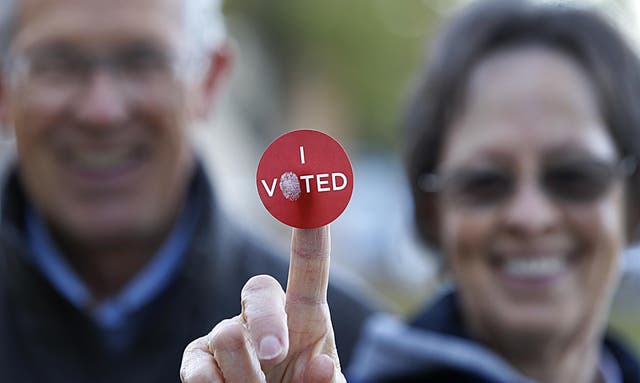 A couple shows off their 'I Voted' sticker as they leave Wasatch Elementary school after casting their ballot in the presidential election on 8 November 2016 in Provo, Utah