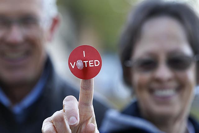 A couple shows off their 'I Voted' sticker as they leave Wasatch Elementary school after casting their ballot in the presidential election on 8 November 2016 in Provo, Utah