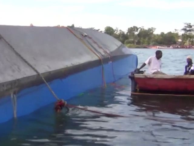 Rescue workers examine the hull of the overturned ferry on Lake Victoria
