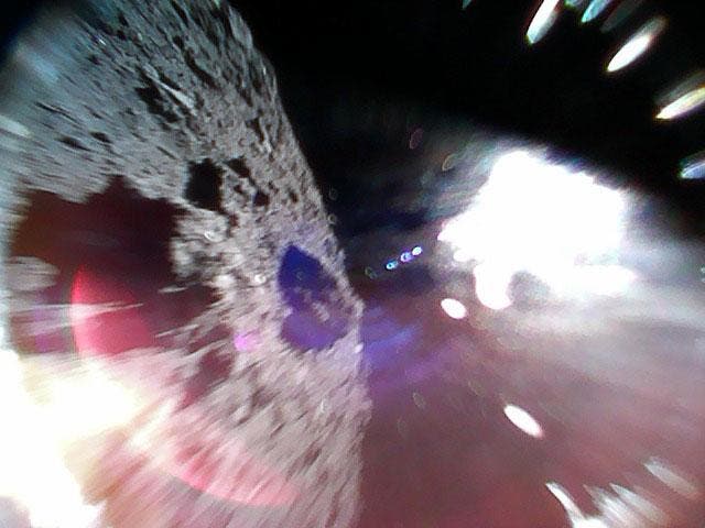 Image captured while one of the rovers was mid-hop on the surface of the Ryugu asteroid. The left of the image is the asteroid surface. The bright white region is due to sunlight