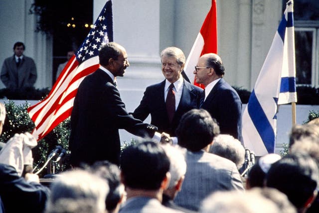 US president Jimmy Carter congratulates Egyptian president Anwar al-Sadat and Israeli premier Menachem Begin as they shake hands on 26 March 1979 on the north lawn of the White House, Washington DC