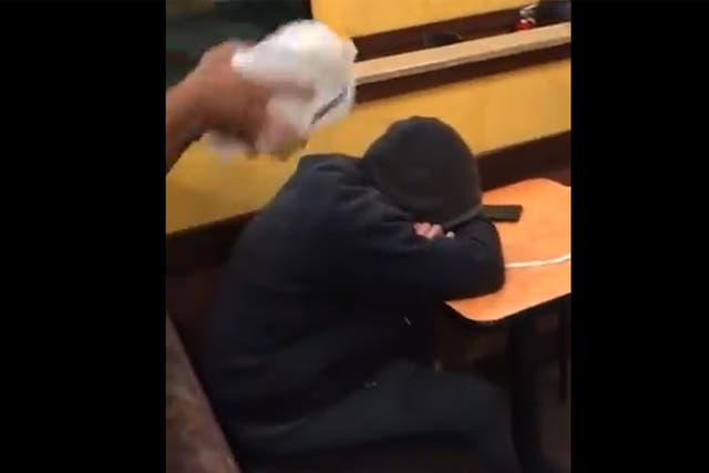 The man is seen resting his head on the table in a Dunkin' Donuts store