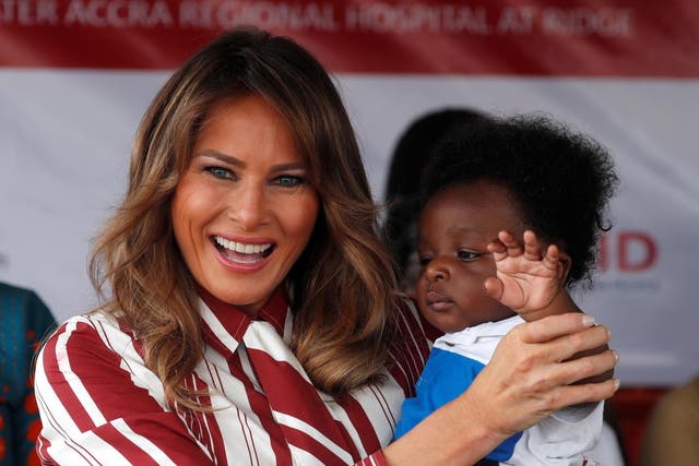 Melania Trump holds a child during a visit to a hospital in Accra