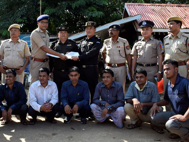 Rohingya men wait to be deported as security officials from India and Myanmar exchange documents