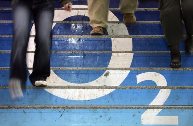 People walk down stairs covered in an ad for British mobile network operator O2
