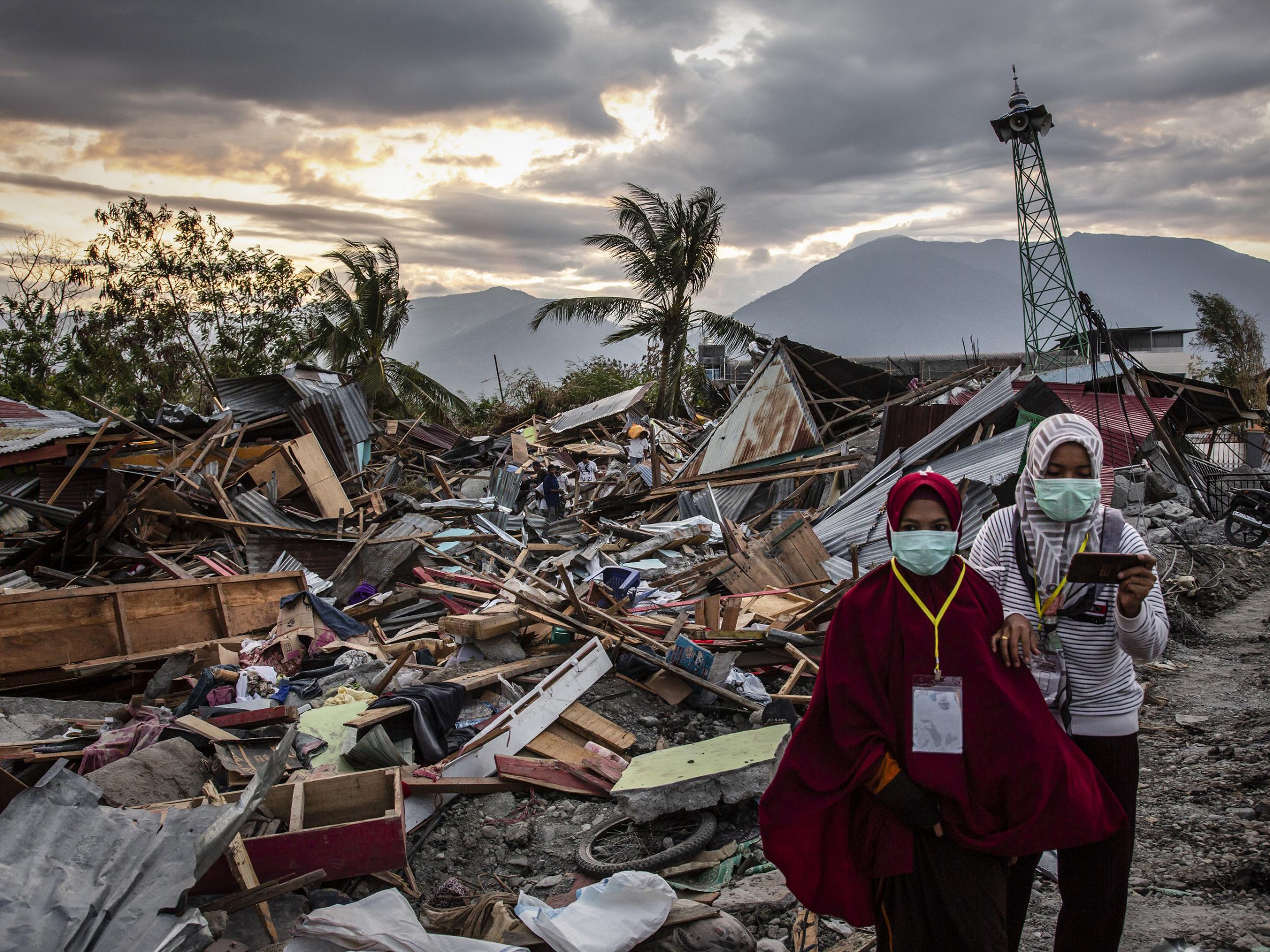 People walk along a damaged area which was hit by liquefaction in Petobo village following the earthquake on October 5, 2018 in Palu