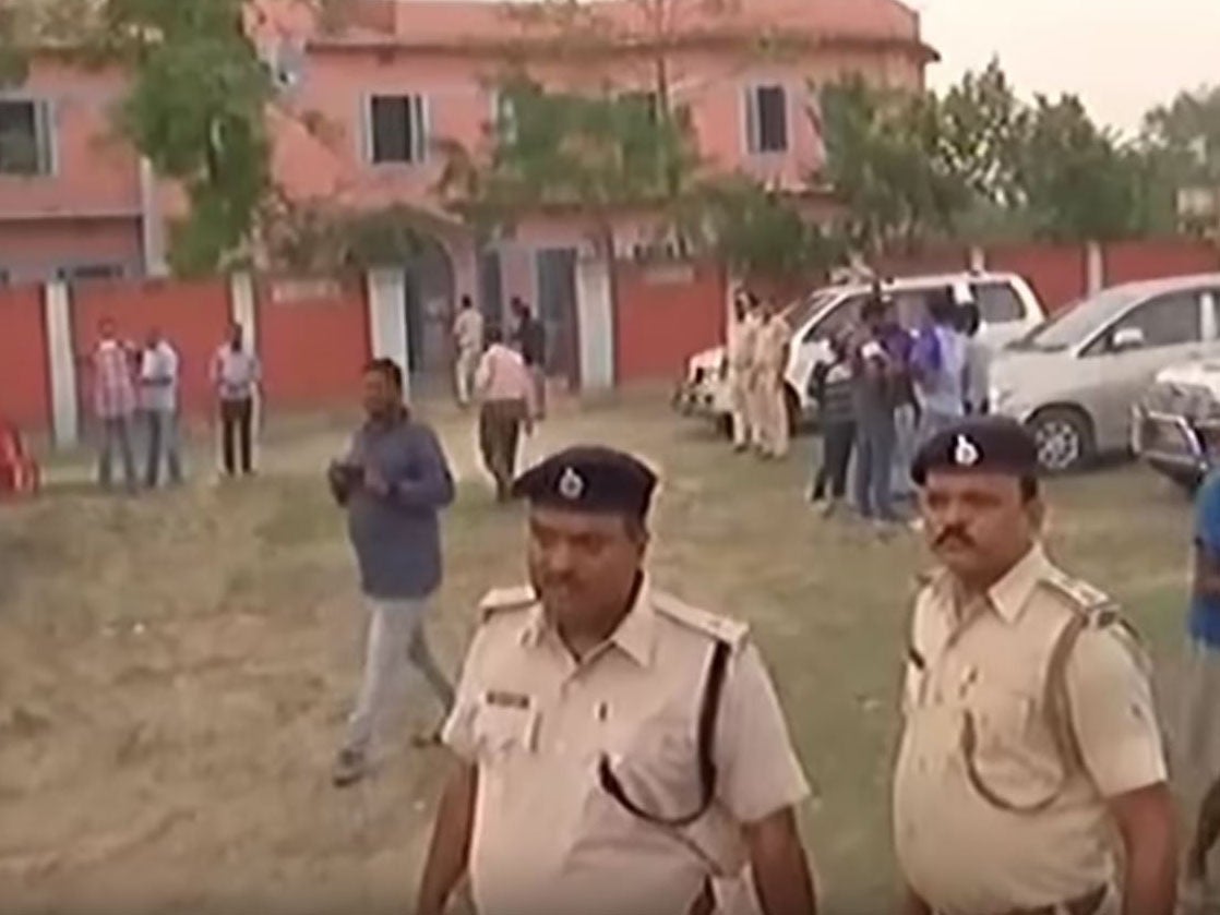 Police officers outside the school where more than 30 girls were beaten by a mob