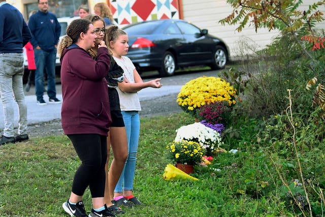 Local residents visit a makeshift memorial established outside of a cafeteria in upstate New York where a nearby limousine crash left 18 passengers and two bystanders dead over the weekend.