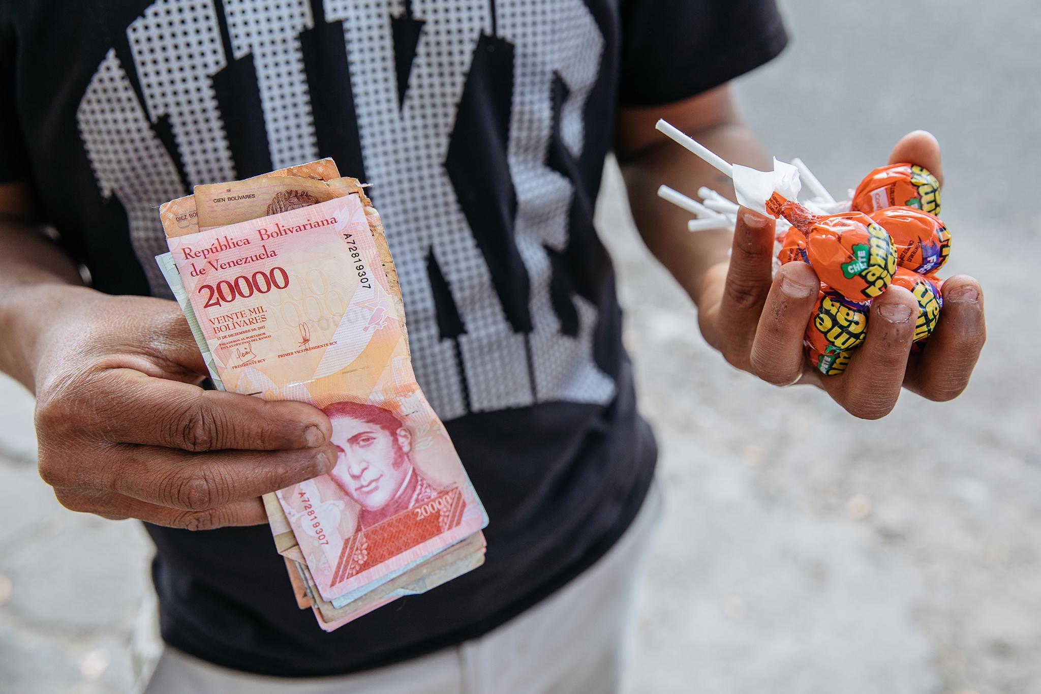 Jesus Bolivar, 29, hands out bolivares with purchases of lollipops in Quito to support his family back home (Paddy Dowling)
