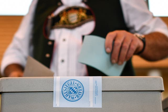 A voter in traditional Bavarian attire casts his ballot at a polling station in Irschenberg