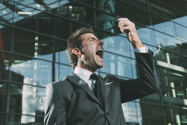 Angry businessman screaming at cell phone outside office building