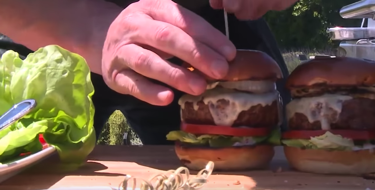 The burgers are finished with grilled onions (YouTube)