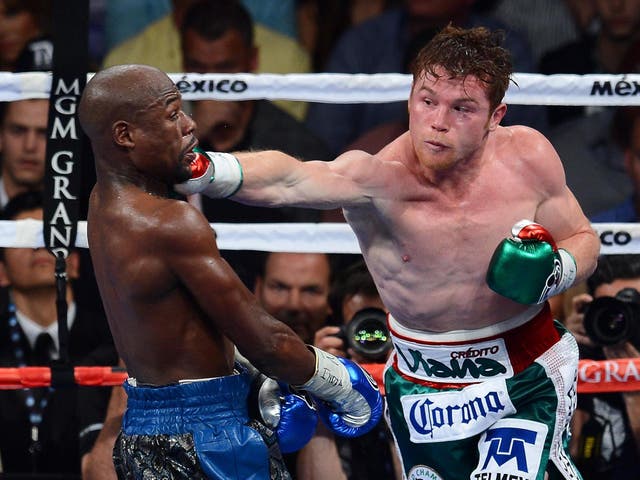 <p>Canelo Alvarez throws a right at Floyd Mayweather Jr.</p>