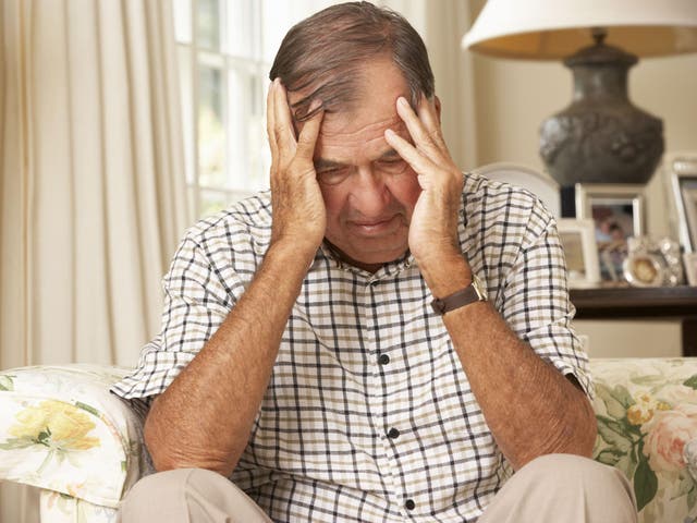 Unhappy Retired Senior Man Sitting On Sofa At Home