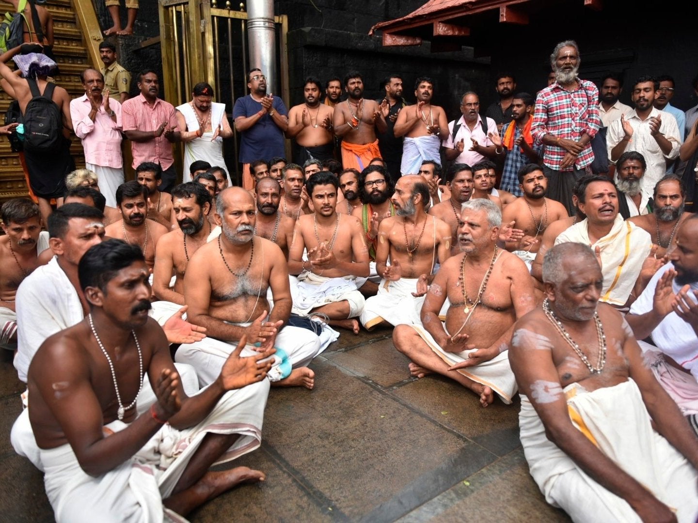 Hindu priests and temple staff sit on a protest against a ruling to let women of menstruating age entering Sabarimala temple