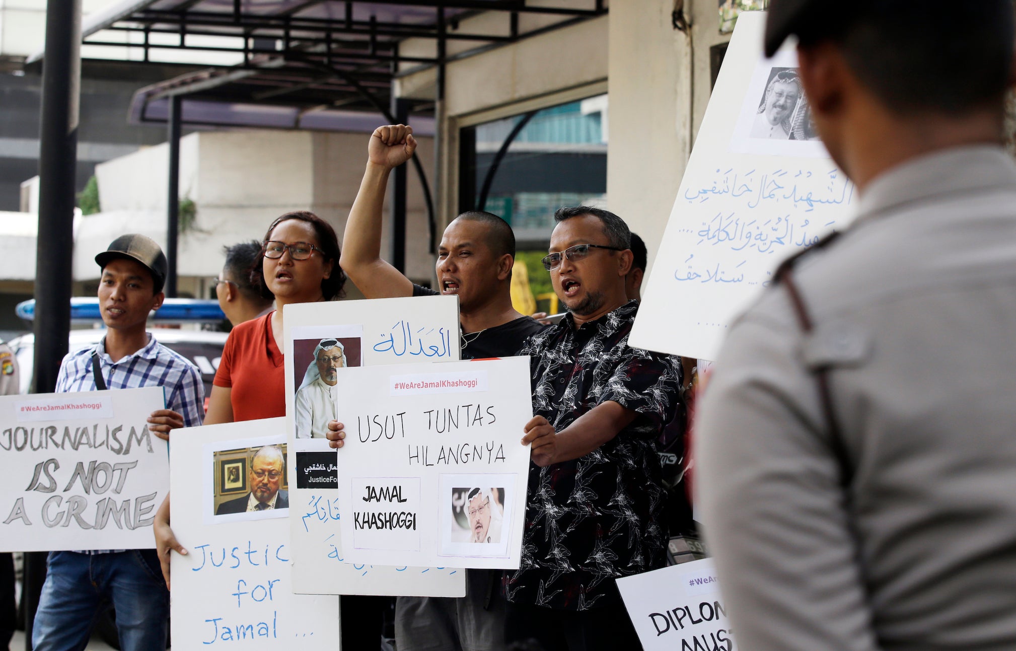 A dozen Indonesian journalists hold posters with photos of Saudi writer Jamal Khashoggi during a protest outside the Saudi embassy in Jakarta, Indonesia, on Friday