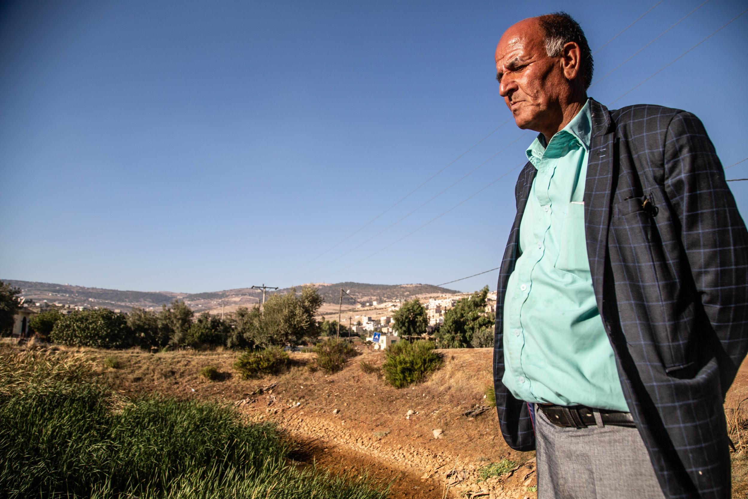 Khaled, 50, a farmer overlooks the dried out pond which once fed his fields