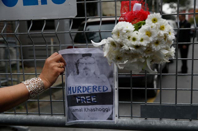 Sahar Zeki, an activist and a friend of slain Saudi writer Jamal Khashoggi, attaches a picture of him and a bouquet of flowers on the barriers blocking the road leading to Saudi Arabia's consulate in Istanbul, Tuesday, Oct. 23, 2018.