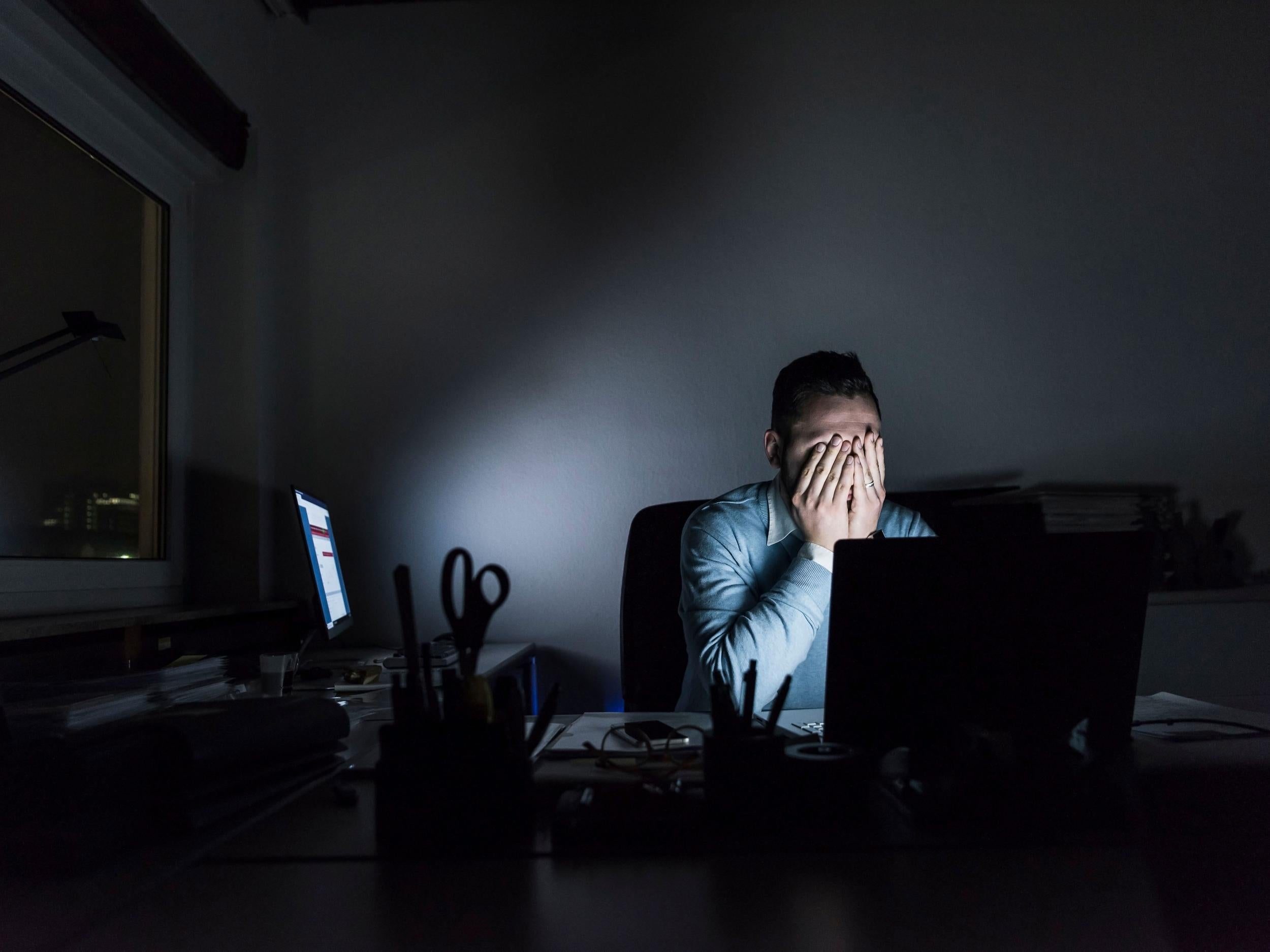 Exhausted businessman sitting at desk in office at night