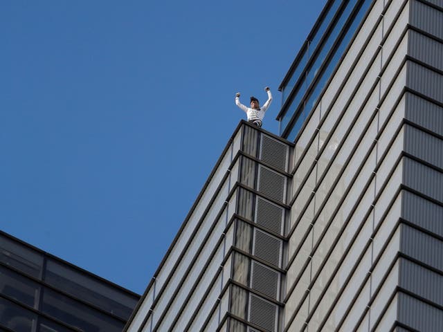 Alain Robert celebrates after climbing Heron Tower unharnessed