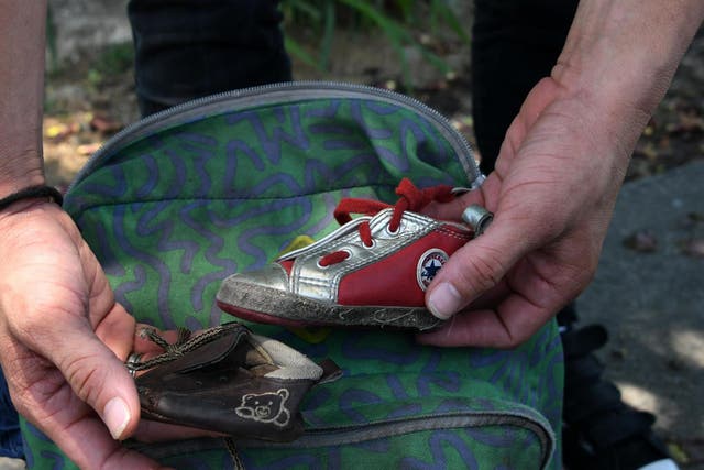 A man shows two little shoes belonging to his eight-month old daughter after being separated from his family, locked up in a Texan detention centre and deported to San Pedro Sula (Photo by ORLANDO SIERRA /