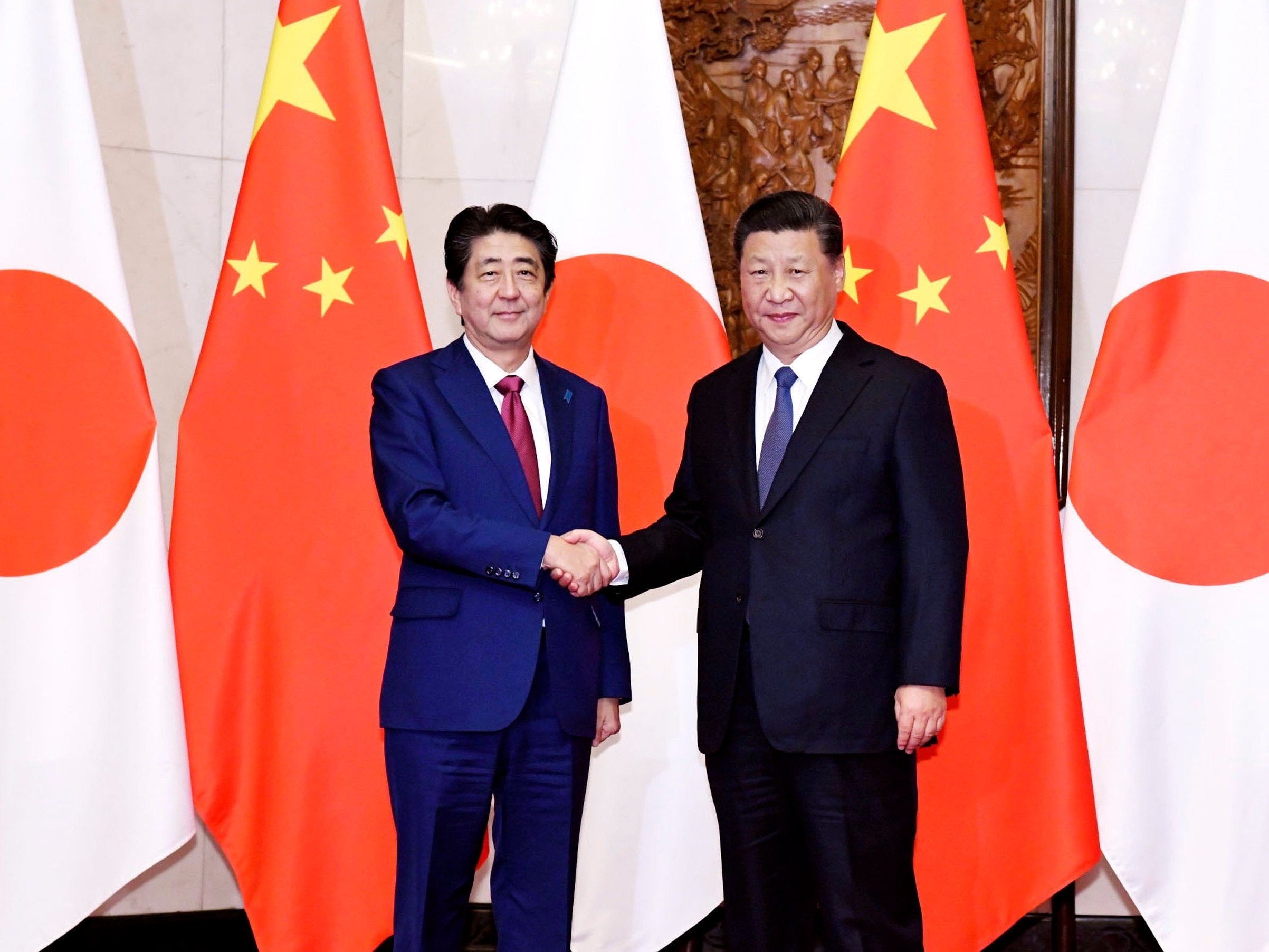 Japanese Prime Minister Shinzo Abe (left), poses with Chinese President Xi Jinping for a photo before a meeting at the Diaoyutai State Guesthouse in Beijing Friday 26 October 2018 (Kyodo News via