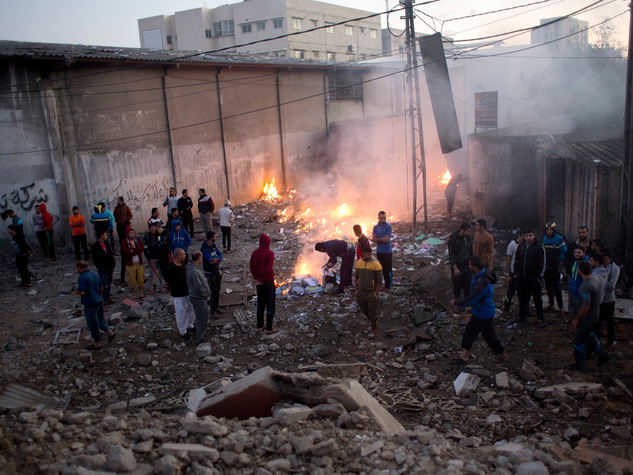 Palestinians check the damage to buildings destroyed by Israeli airstrikes