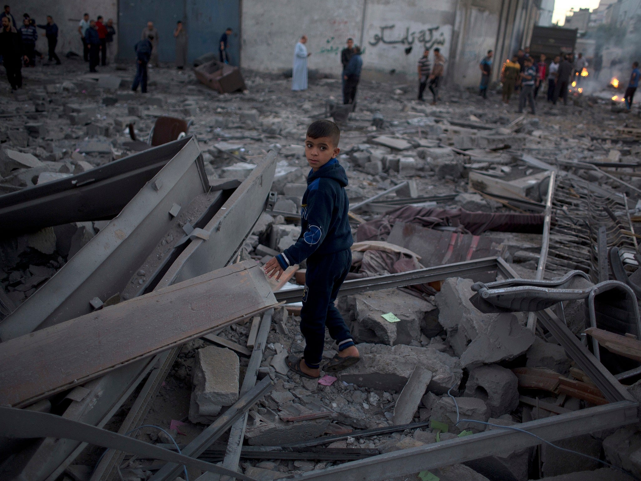 A Palestinian boy stands amid the rubble of buildings destroyed by Israeli airstrikes