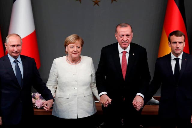 Russian President Vladimir Putin, German Chancellor Angela Merkel, Turkish President Recep Tayyip Erdogan and French President Emmanuel Macron hold hands after a conference as part of a summit called to attempt to find a lasting political solution to the civil war in Syria