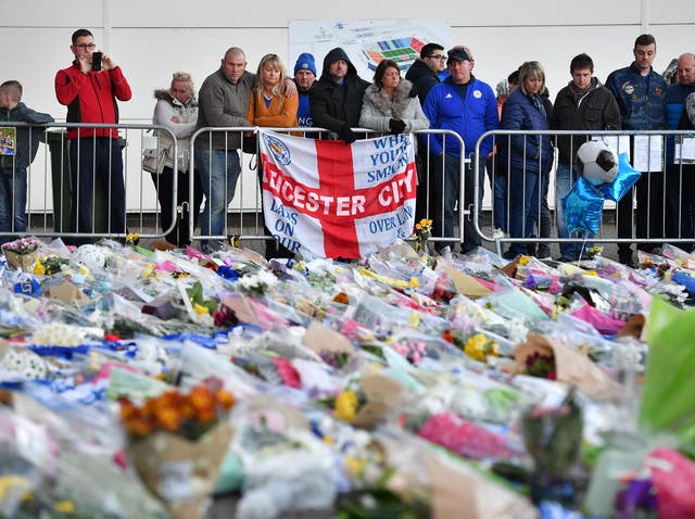 Supporters pause at the pile of floral tributes