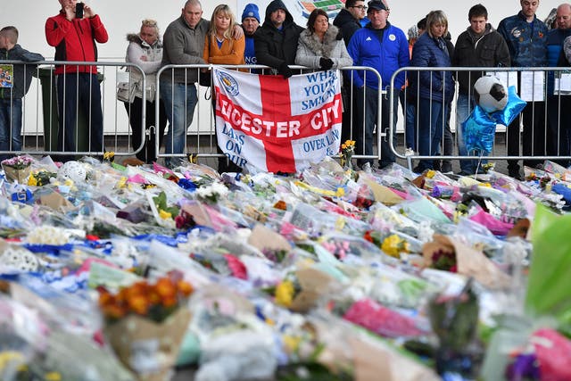 Supporters pause at the pile of floral tributes