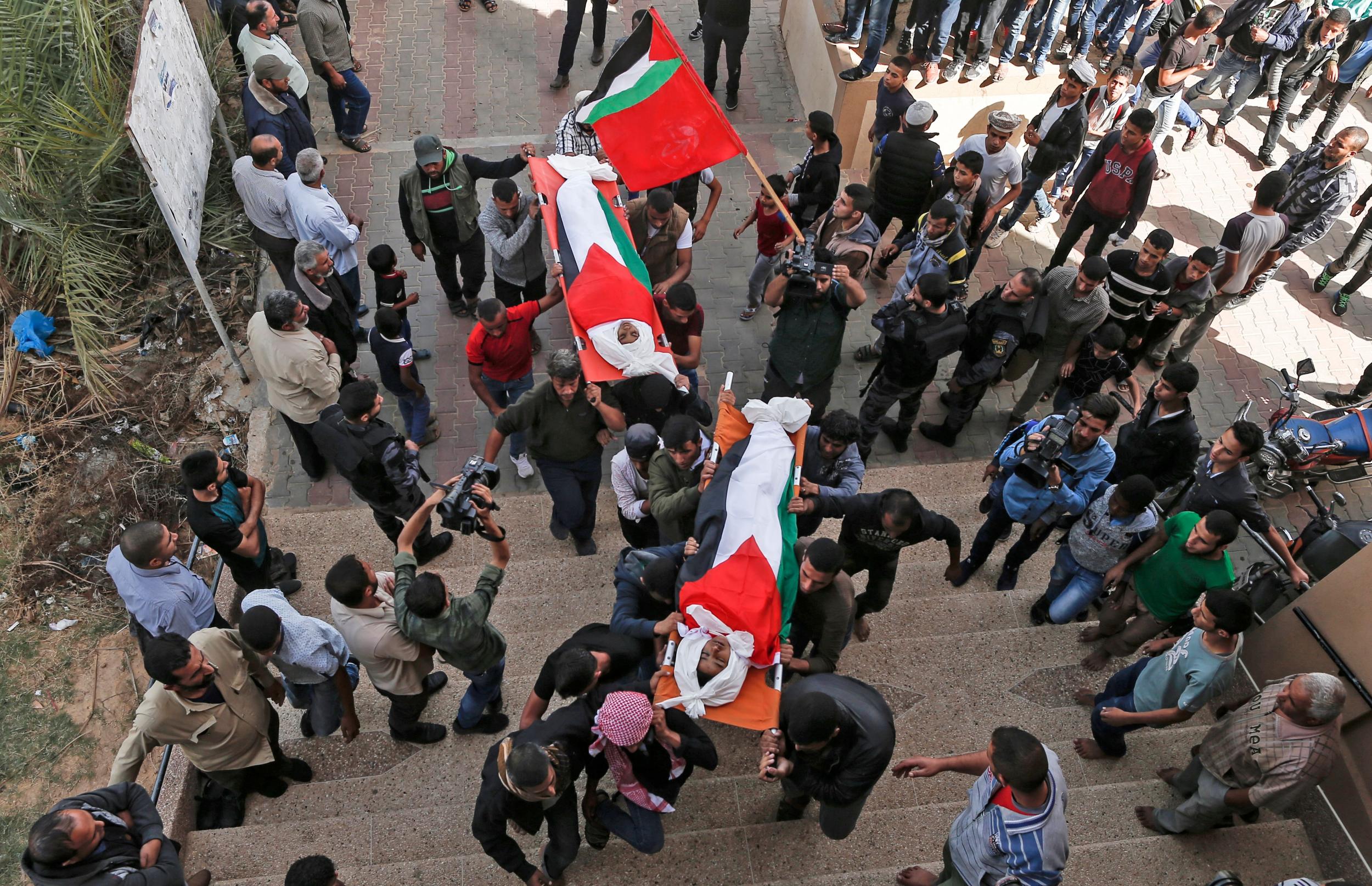 Palestinian mourners carry the bodies, draped in their national flag, of two of the three teenagers who were killed in an Israeli strike during their funeral in Deir el-Balah in the central Gaza Strip Photo: MAHMUD HAMS/AFP/Getty Images