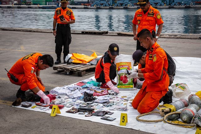 Search and rescue personnel examine recovered personal items from Lion Air flight JT 610 at the Tanjung Priok port