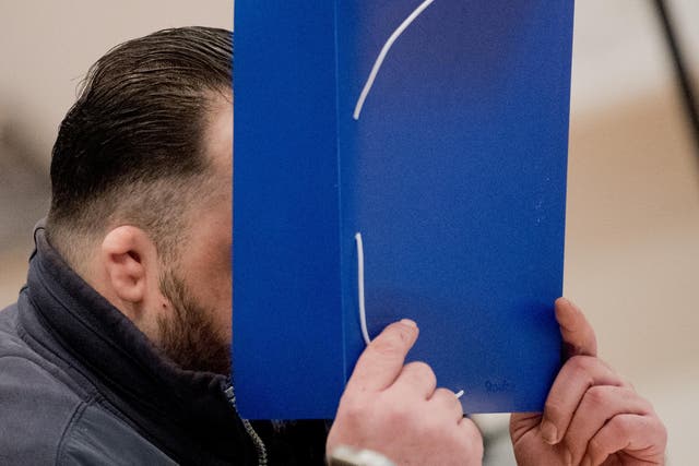 Niels Hoegel covers his face as a he arrives for his trial at a court in Oldenburg, Germany