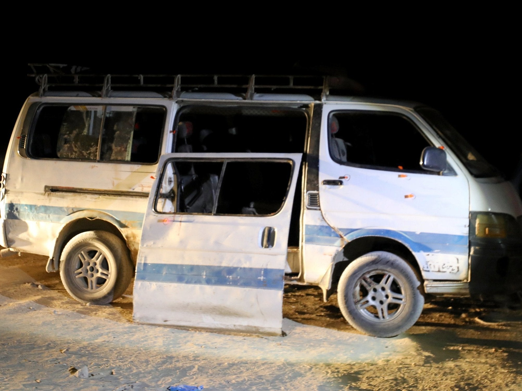 Policemen stand beside the microbus which carried Coptic Christians when gunmen opened fire