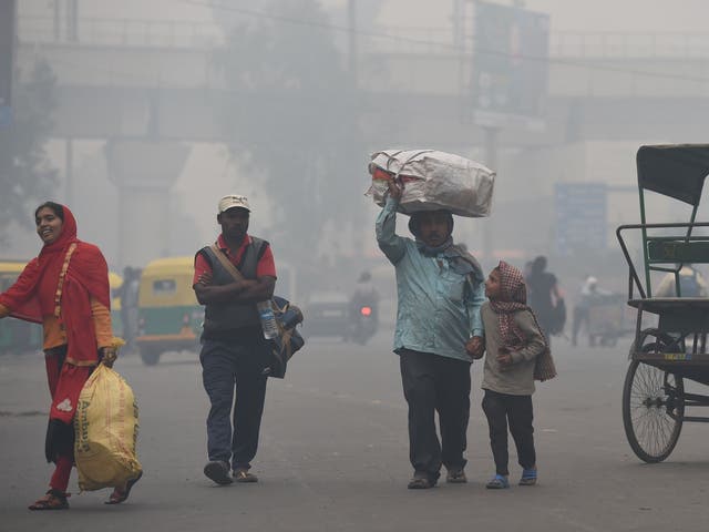 A man carries his belongings in heavy smog in Delhi on 5 November