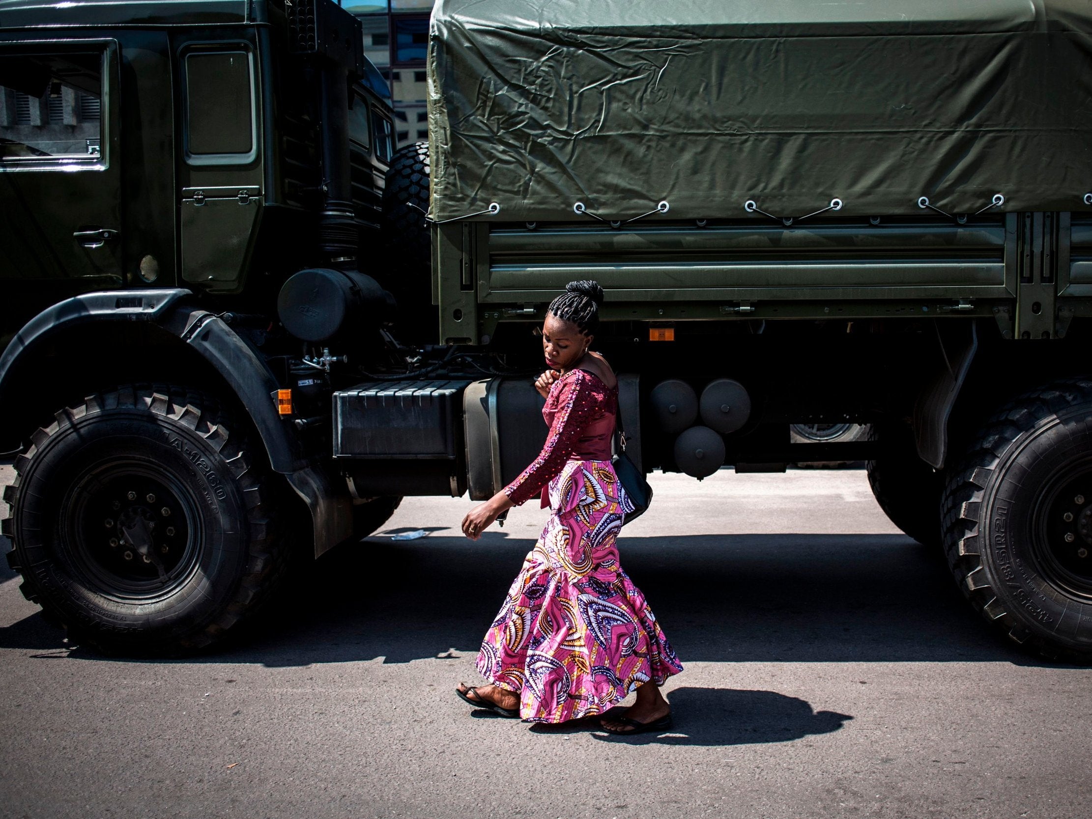 Woman walks past military lorries in Kinshasa ahead of DRC elections (Getty)