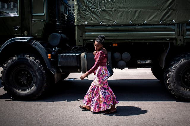 Woman walks past military lorries in Kinshasa ahead of DRC elections (Getty)