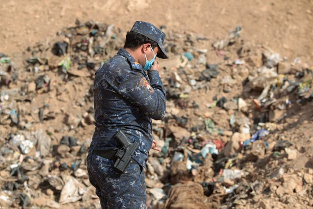 A member of the Iraqi forces checks a mass grave they discovered in Iraq in 2016, after they recaptured the area from Isis