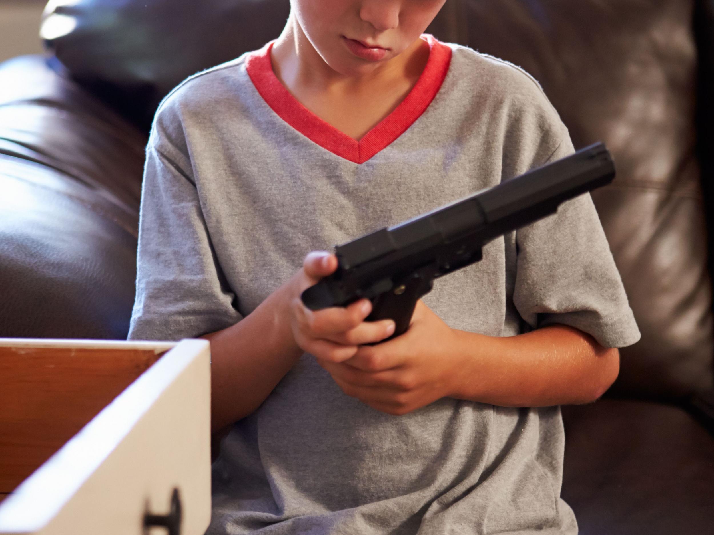 Boy Playing With Parent's Gun He Has Found At Home